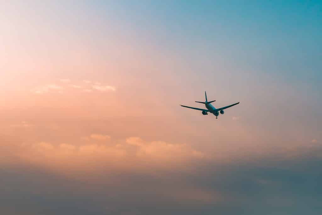 Airplane flying in the sky in red clouds. 