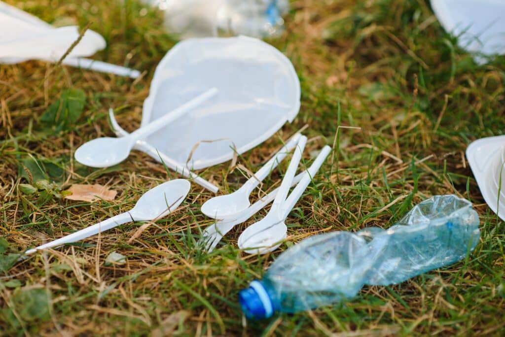 Hromada plastů na zelené trávě, problém v přírodním prostředí, znečištění přírody není rozklad plastů. Ochrana přírody.